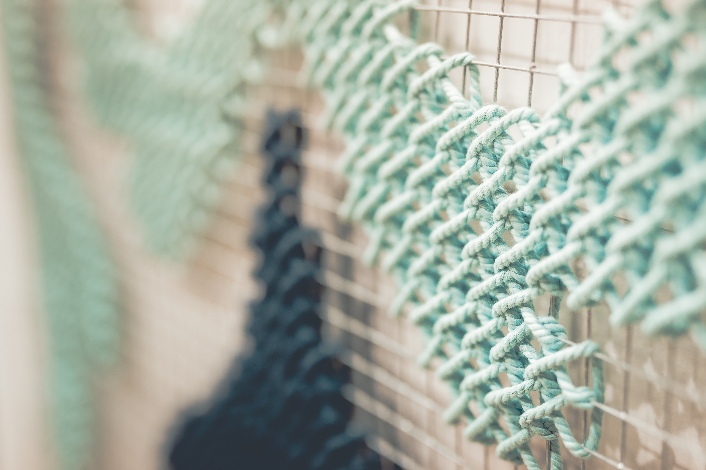 Gayafores — macro detail of turquoise embroidery stitch on metallic mesh